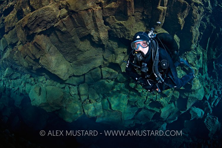 A diver explores  Silfra canyon, a deep fault filled with fresh water in the rift valley between the Eurasian and American tectonic plates) at Thingvellir National Park, Iceland. In this photo the wall behind the diver is the Eurasian plate. Model released.