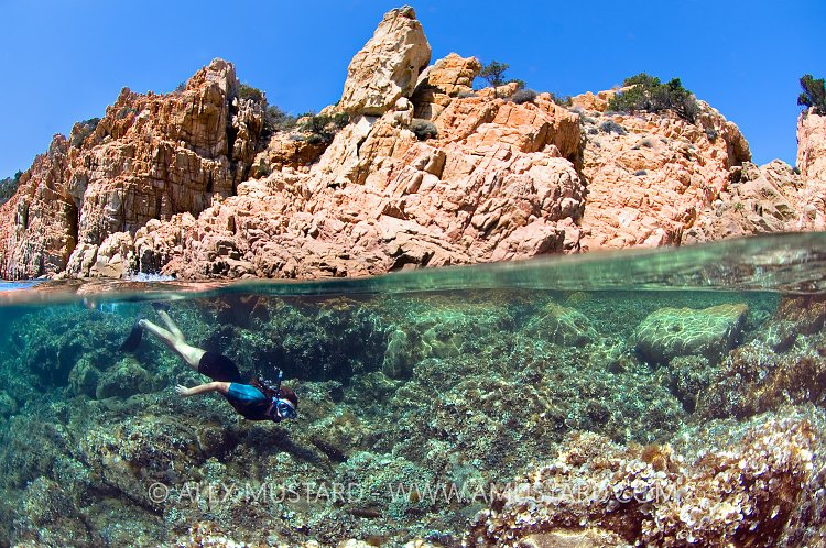 Snorkeller Beneath Rocks. Sardinia, Italy.