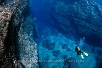 Diver Approaches Underwater Cavern. Sardinia